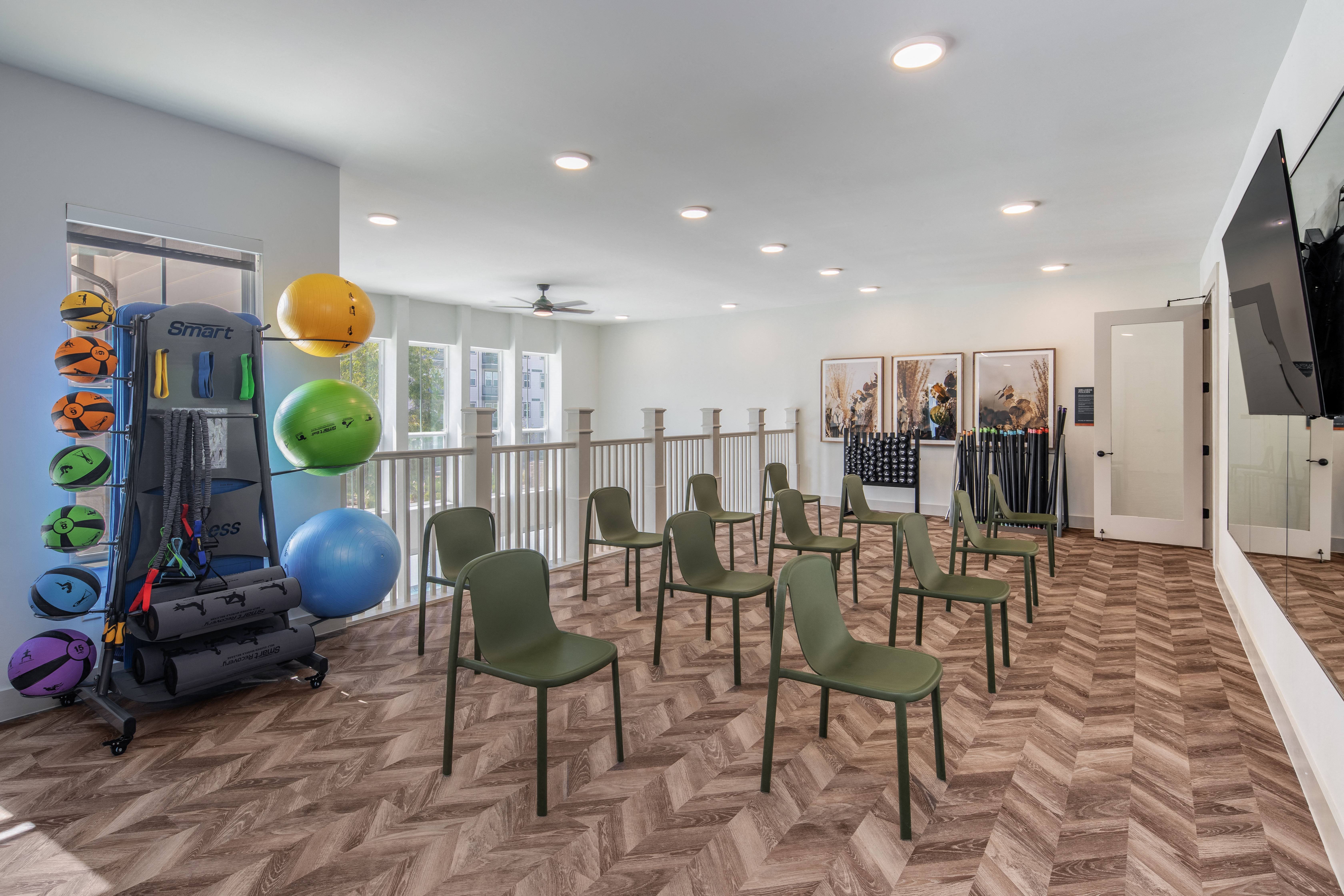 a fitness room with chairs and a table with weights and a television